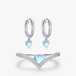 An image of a heart ring set and matching earrings, crafted with sterling silver and adorned with shimmering moonstone