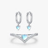 An image of a heart ring set and matching earrings, crafted with sterling silver and adorned with shimmering moonstone